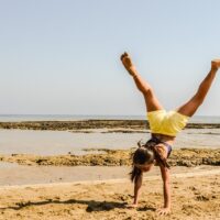 girl doing handstand on the beach- Summer Fitness Tips to Beat the Heat