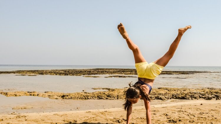 girl doing handstand on the beach- Summer Fitness Tips to Beat the Heat